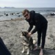 Mann på stranden med hunden sin